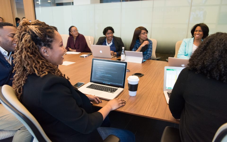 A marketing team reviewing campaign plans around a laptop
